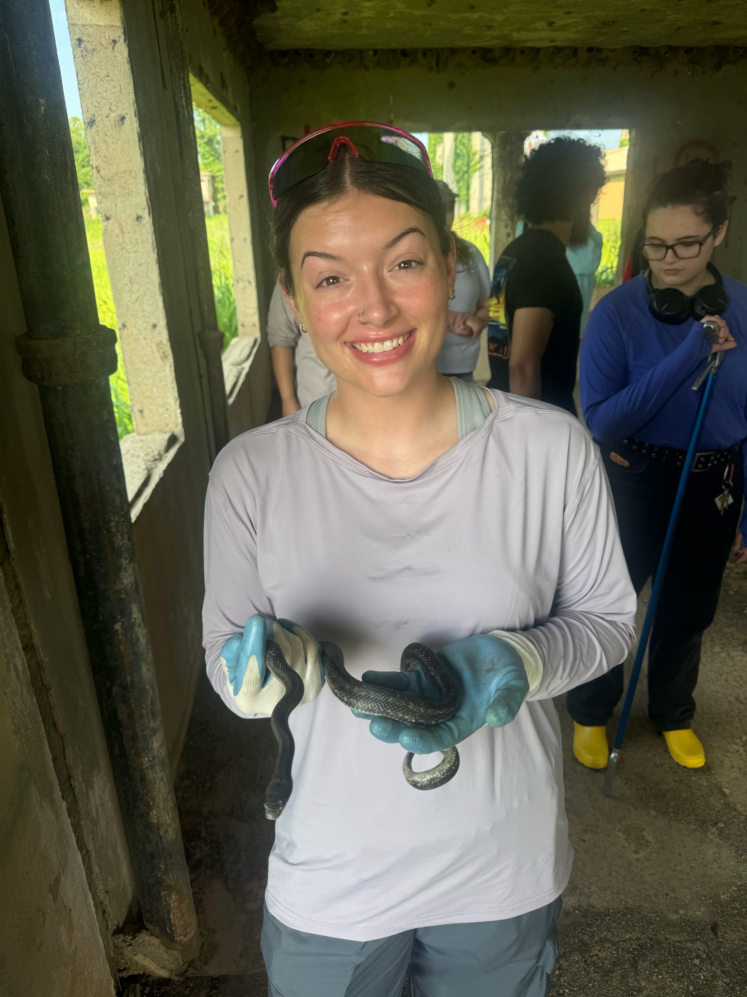Student wearing gloves holds a snake while participating in a supervised wildlife handling activity at the biological station.
