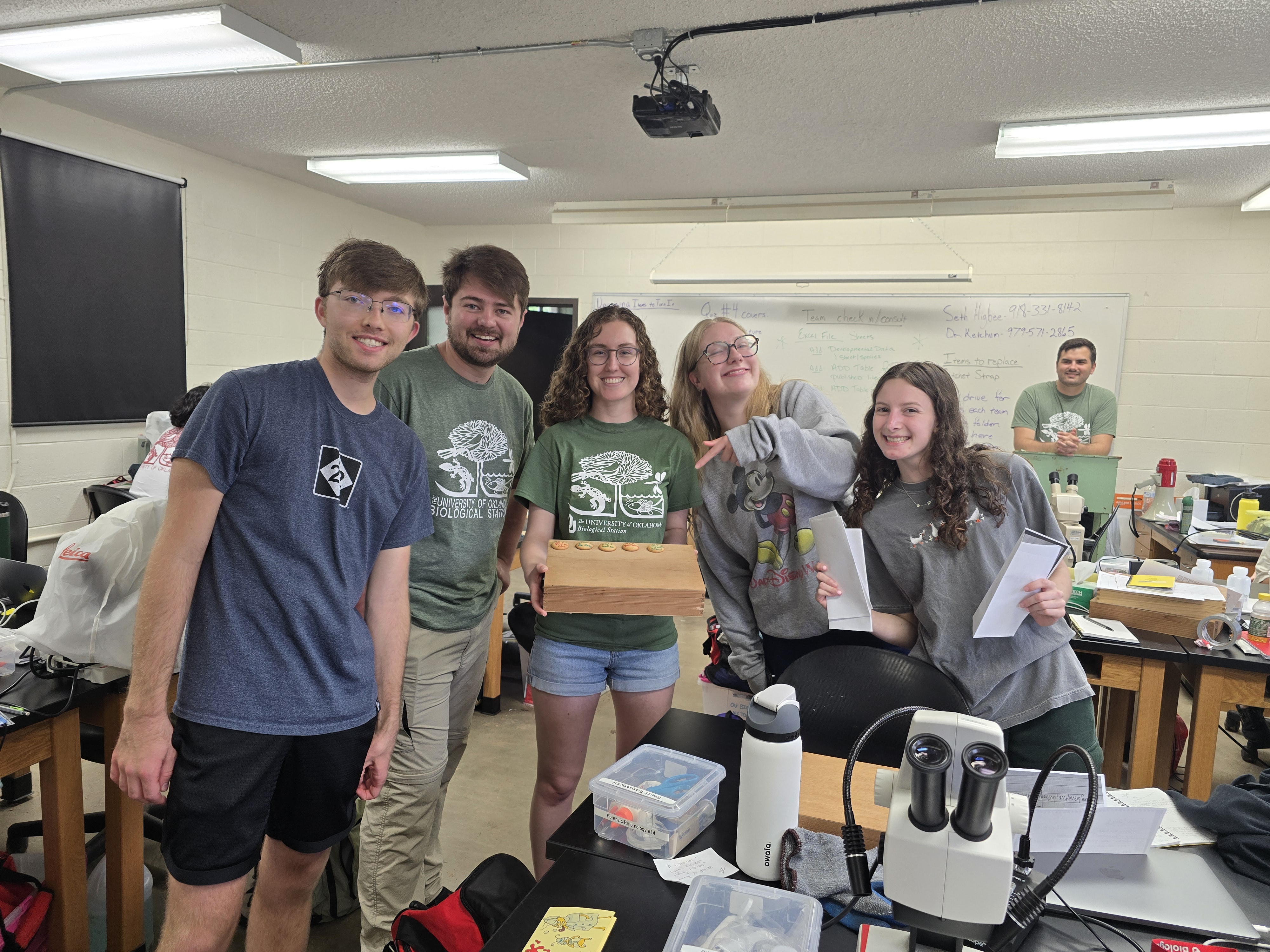 Group of students standing together in a biology classroom laboratory with microscopes and equipment during a hands-on learning session at the biological station.