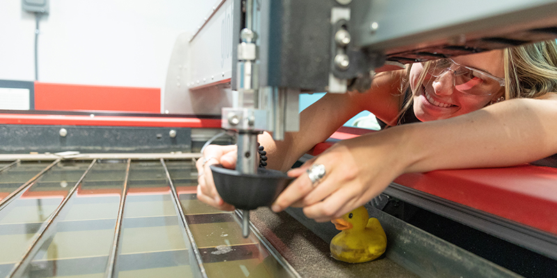 A young female students works one of the machines in the fabrication lab at the IHub on the Norman, OK campus.