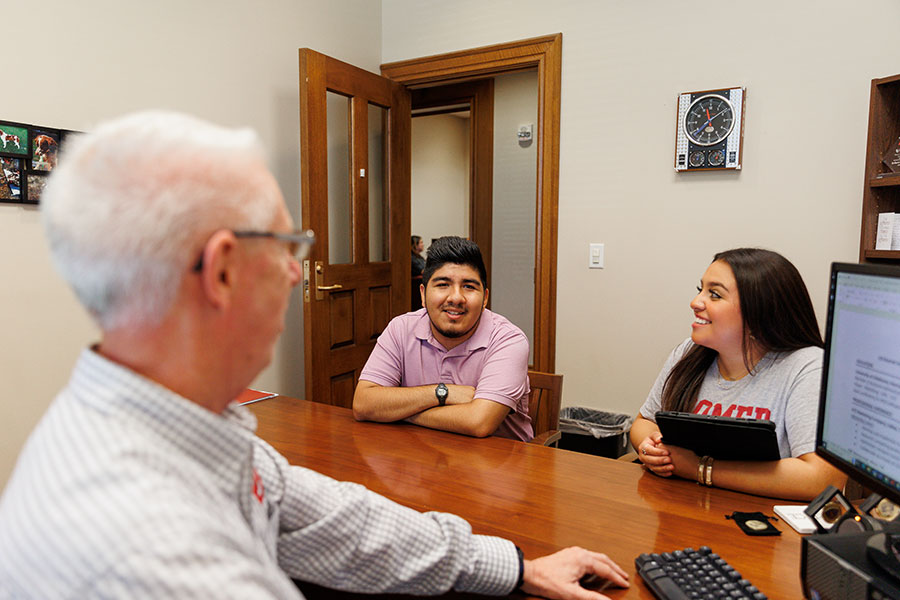 A career services staff member meeting with two students in their office.