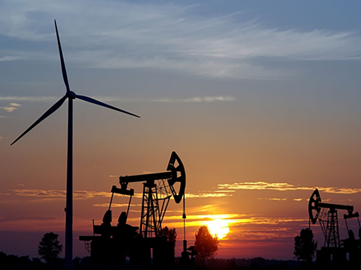 a sky at sunset with wind turbine and oil derrik's silhouetted against the settting sun.