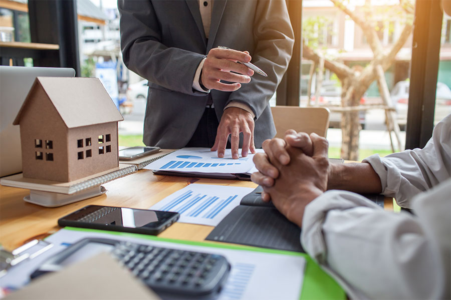 Two people at a desk looking over home and finance plans.