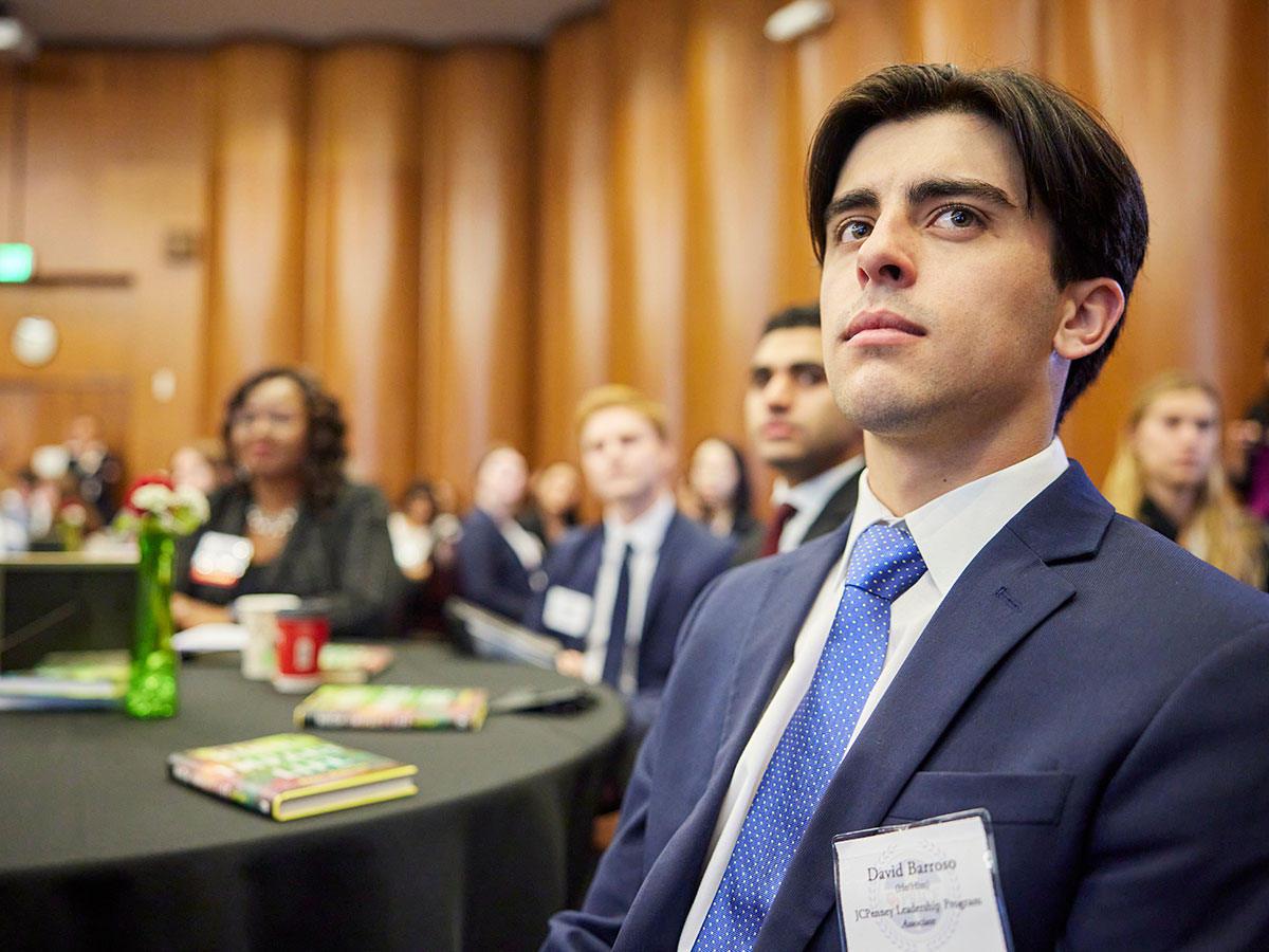 A speaker addressing the audience from a podium at the front of the room. 