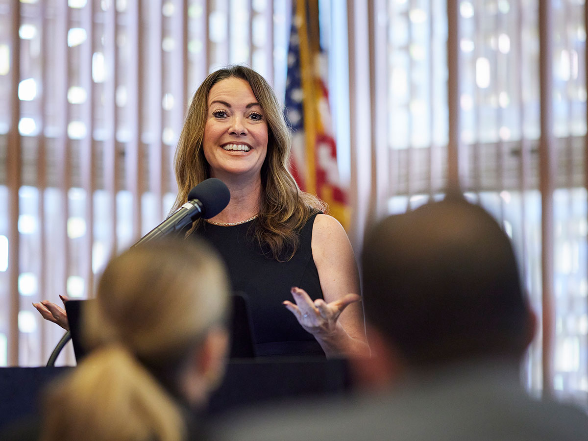 A speaker addressing the audience from a podium at the front of the room. 