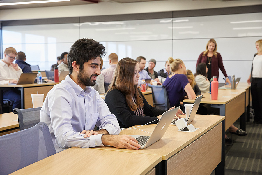 Students in an MBA classroom taking notes on laptops while listening to the lecture.
