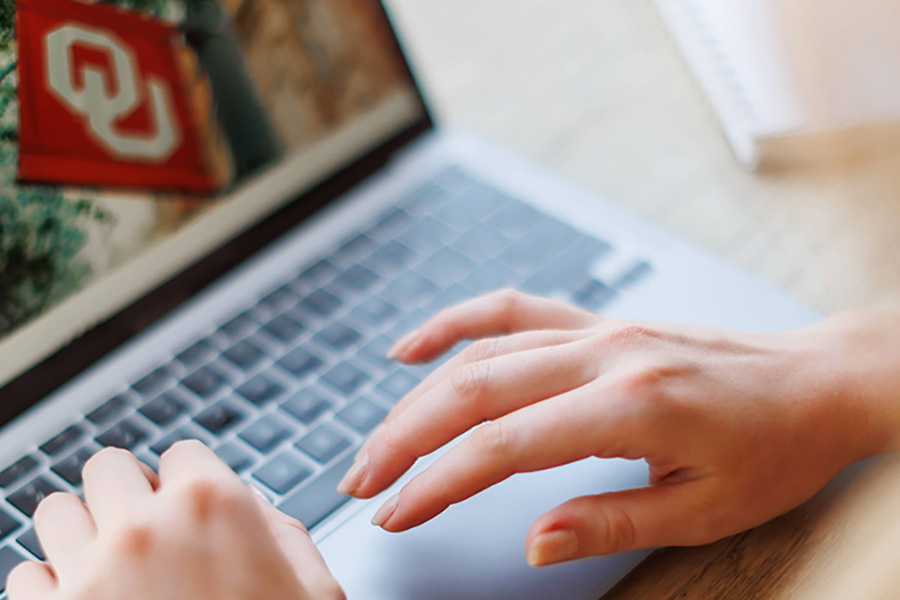 hands typing on a laptop.