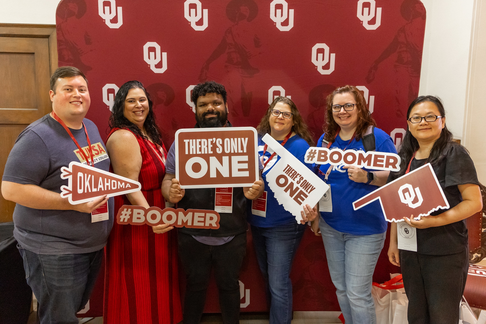 Six people standing looking in front and showing OU banners.