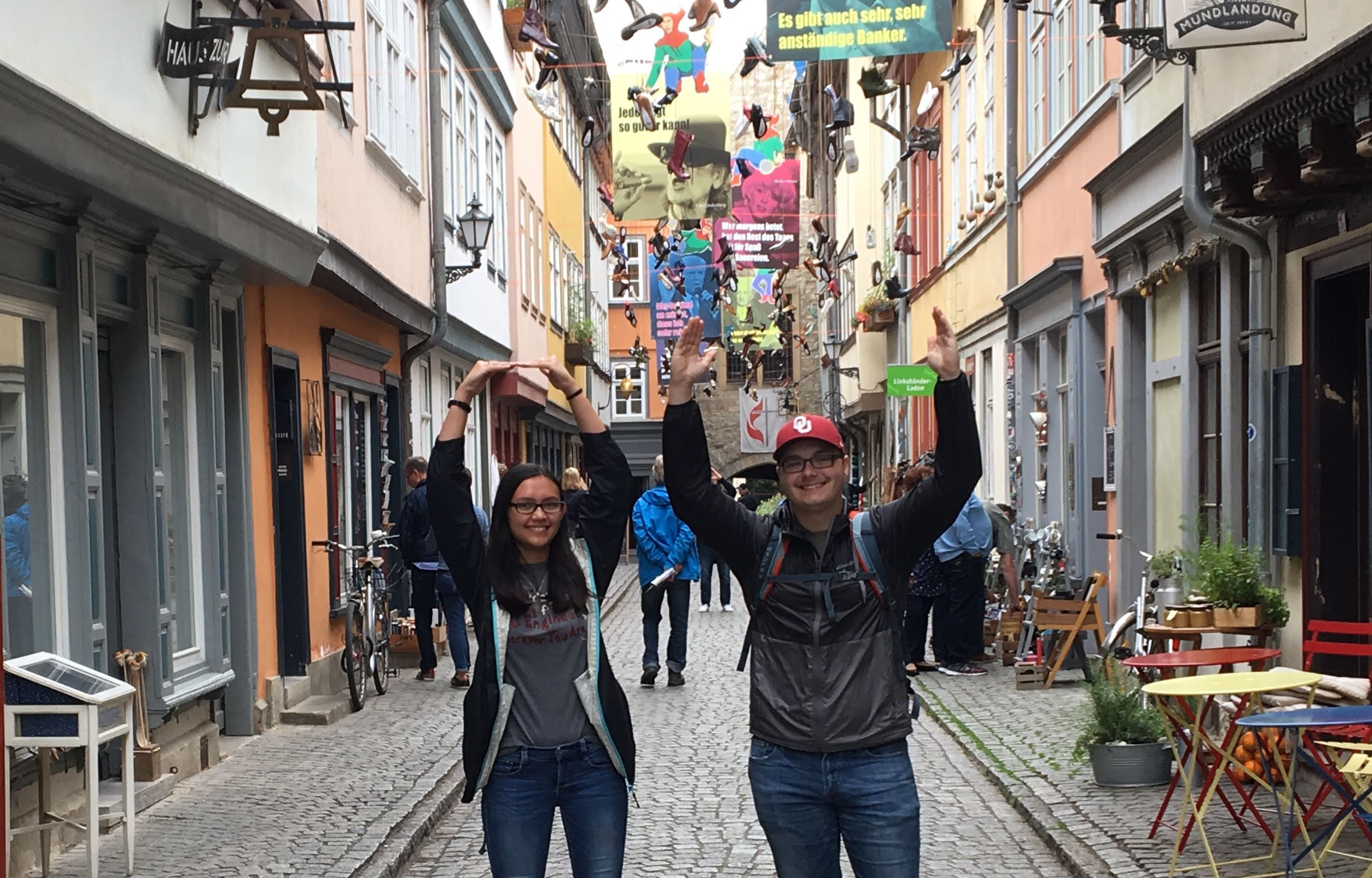 Two people posing for the camera and putting up the OU sign with their arms. 