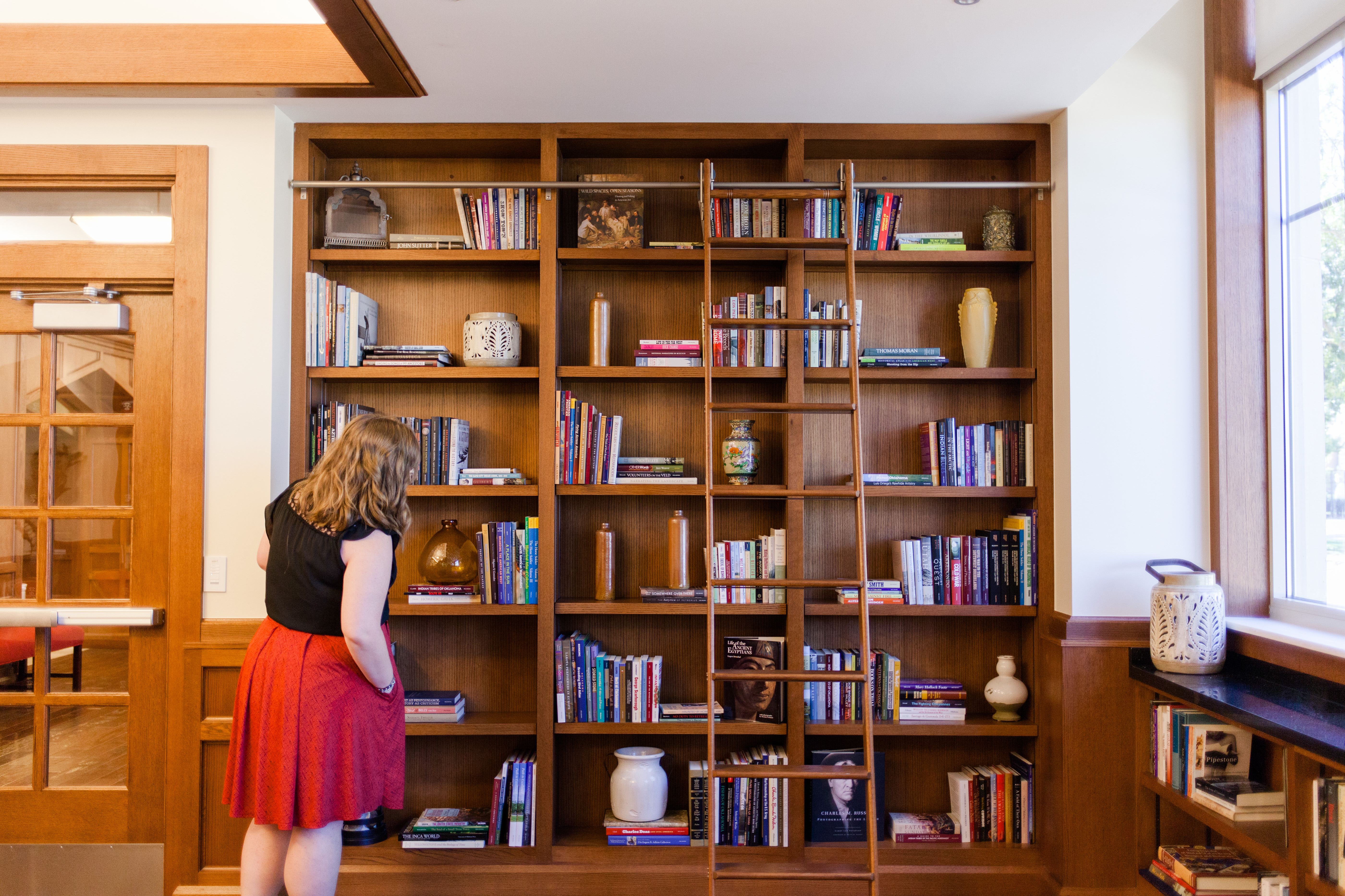 student looking for a book at a floor to ceiling bookshelf