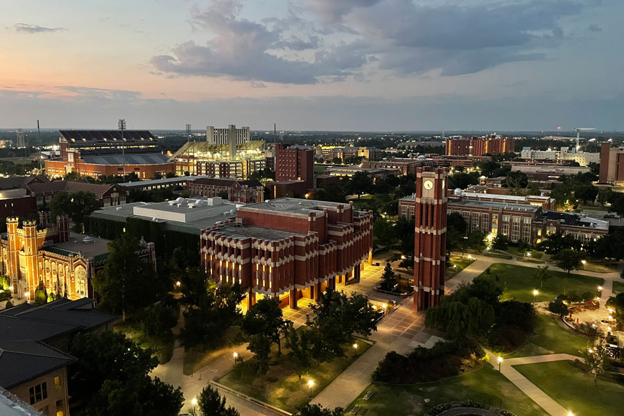 An aerial view of campus at dawn with the sun rising and building lights casting a yellow glow.