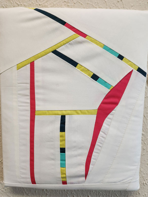 An outline of a house in red, yellow, black, and teal fabrics.