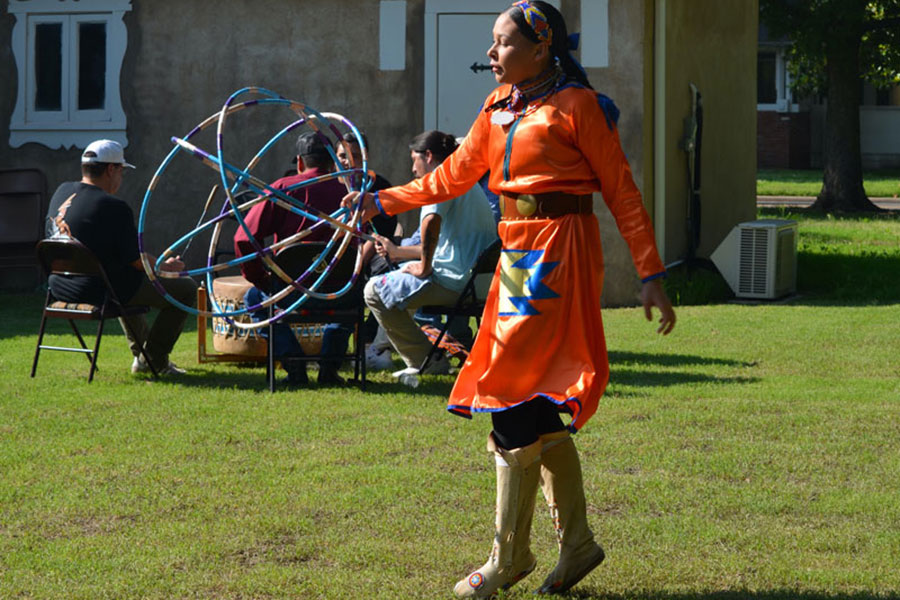 A hoop dancer dressed in orange performs at the Jacobson House. 