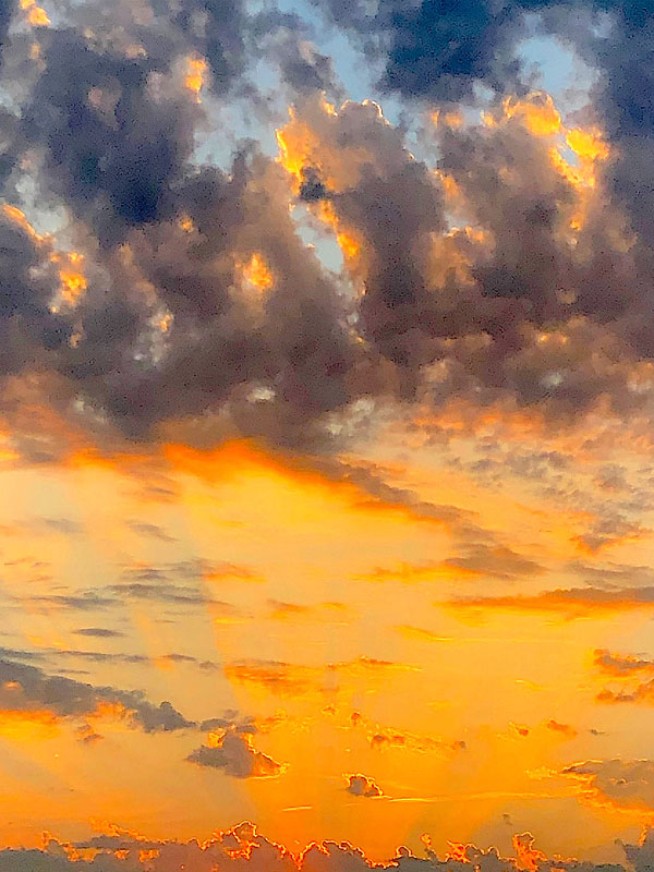 A orange sunrise fading into grey and blue clouds.