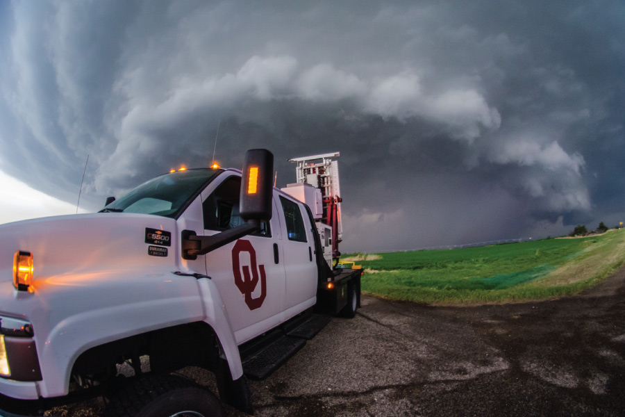 An OU radar truck with a large storm in the background.