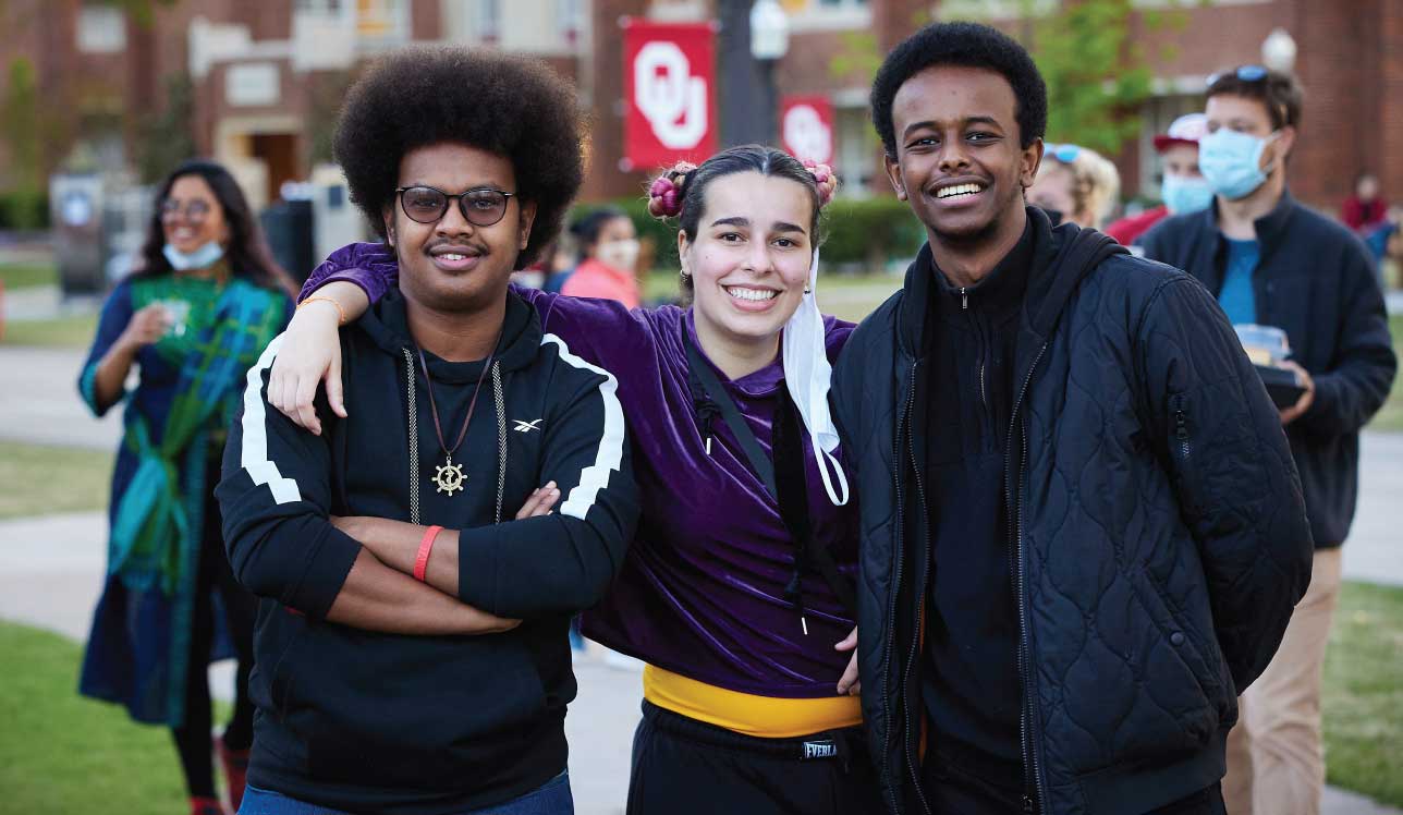 Three smiling multinational students outside on Oklahoma University Campus