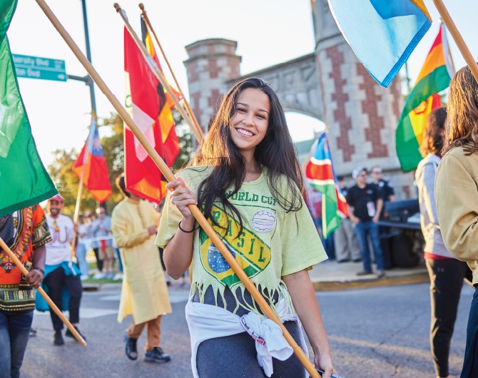 A smiling multinational student carries a flag