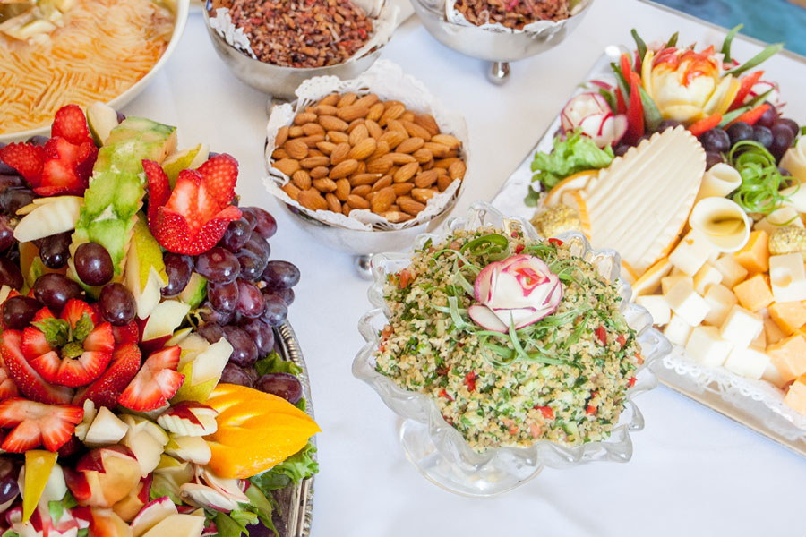 Multiple large bowls/trays of food on a white table.