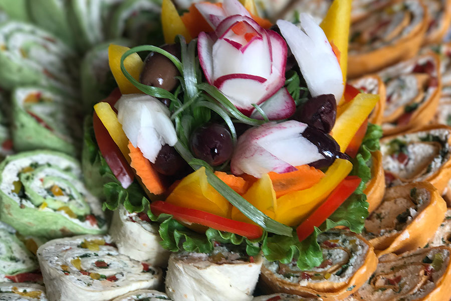 Multiple rollups food items with a decorative flower made from food in the middle.