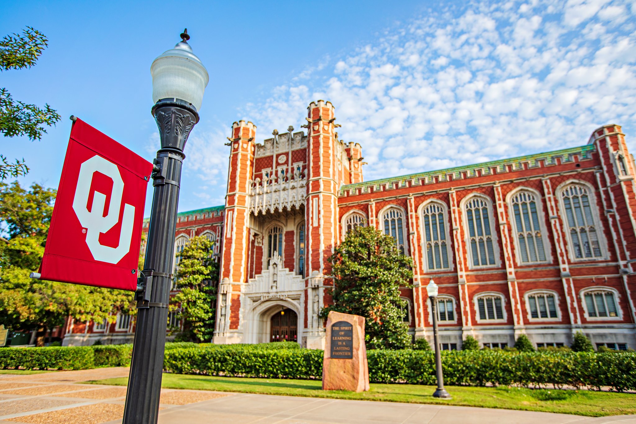 White shot of the Bizzell Memorial Library with an OU banner on a lightpost out front.