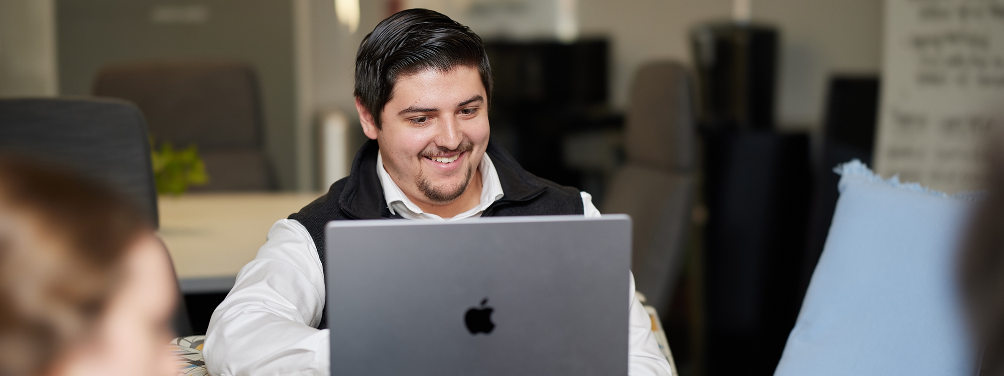 Students sitting at a table, working on laptops.