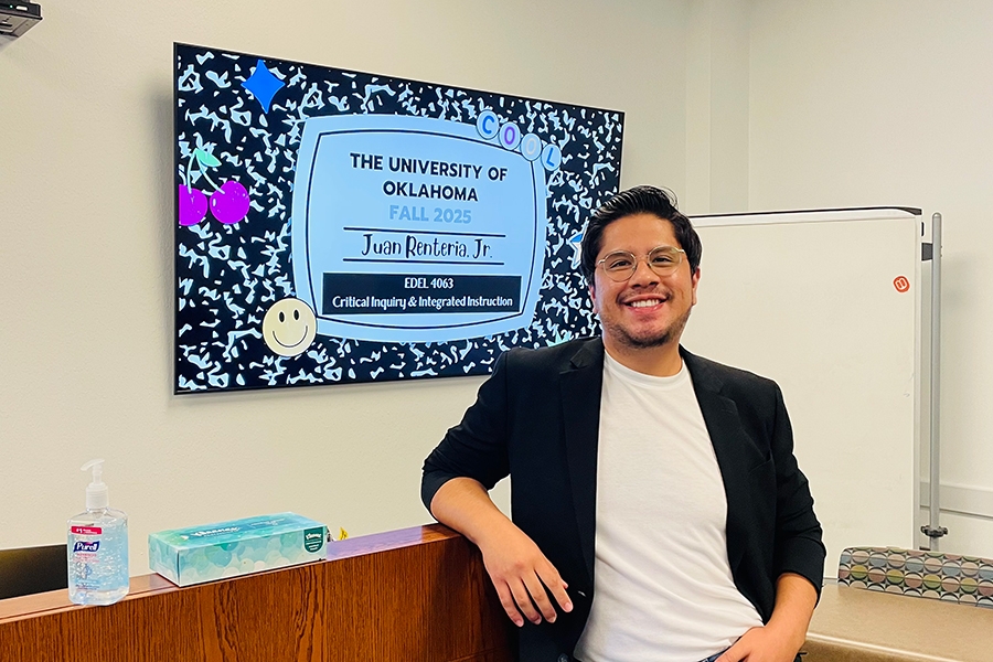 Juan Renteria posing for a photo in front of a television screen.