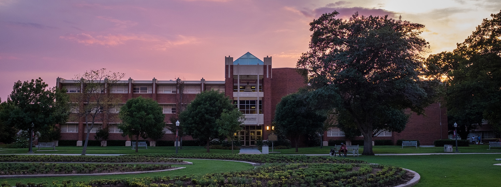 Collings Hall at sunset, surrounded by greenery.