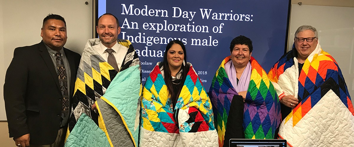 Johnny Poolaw and faculty with native quilts