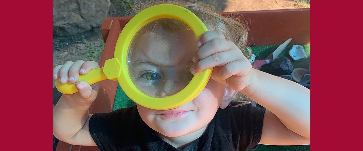 Child looking through magnifying glass
