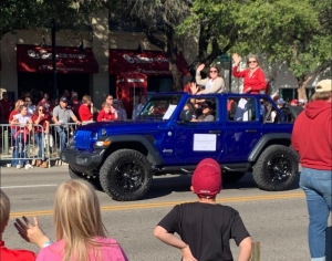 Stacy Reeder and Jessica Eschbach riding in a blue Jeep and waving