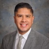 Headshot of Juan Renteria with a grey background wearing a grey sport coat and white shirt