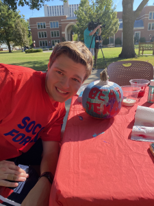 Student in a red shirt posing next to his pumpkin that says Beat Texas