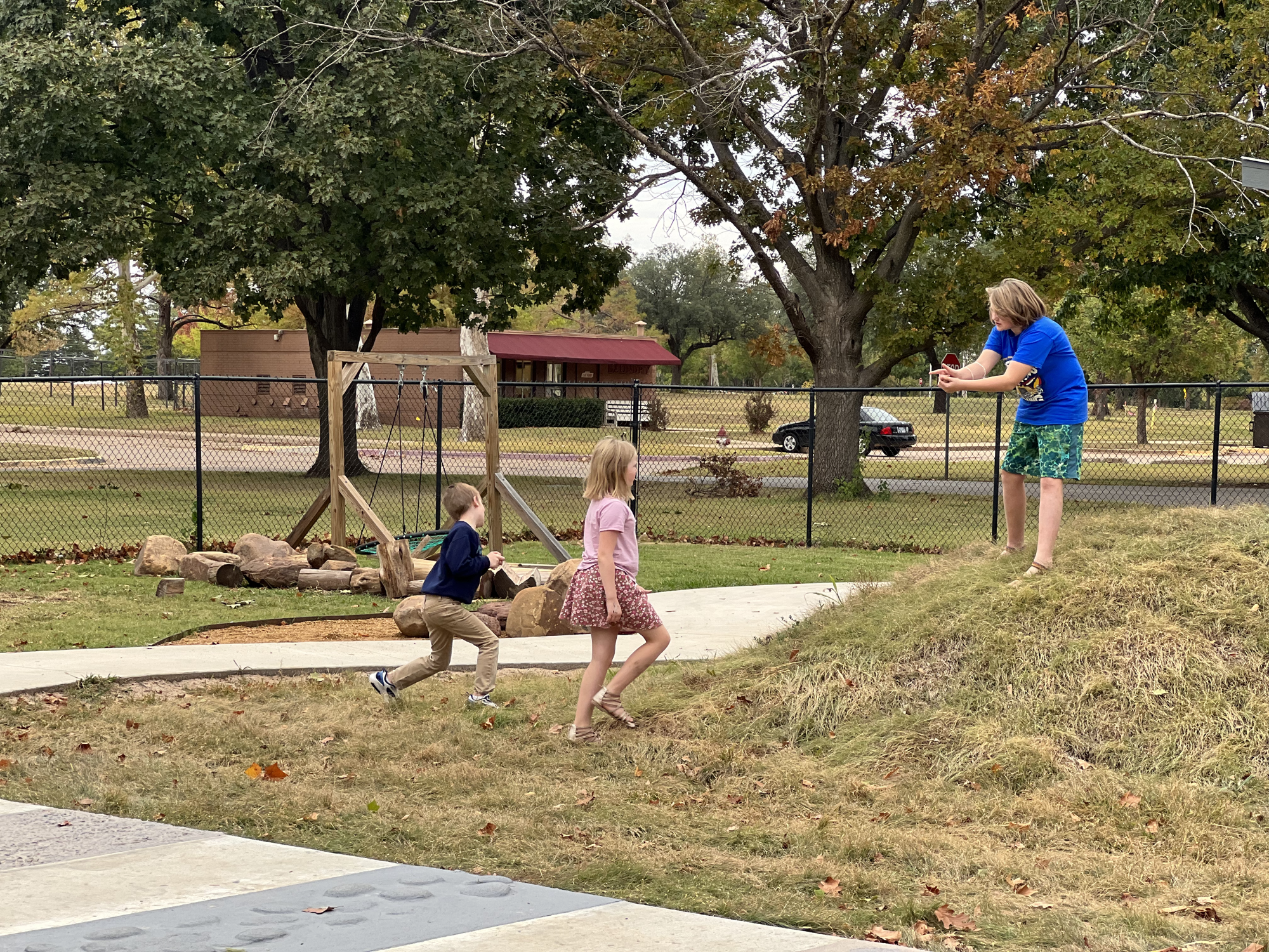 3 children playing outside on a hill