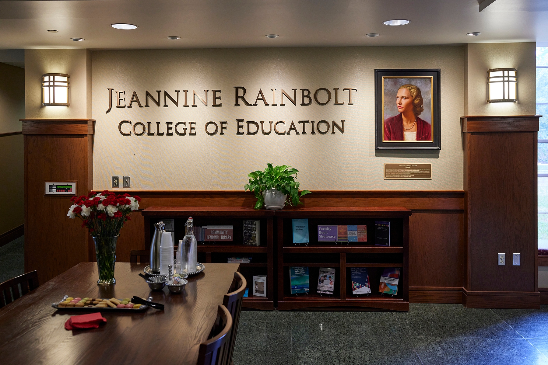 The words Jeannine Rainbolt College of Education on a wall with a portrait of Jeannine Rainbolt next to it.
