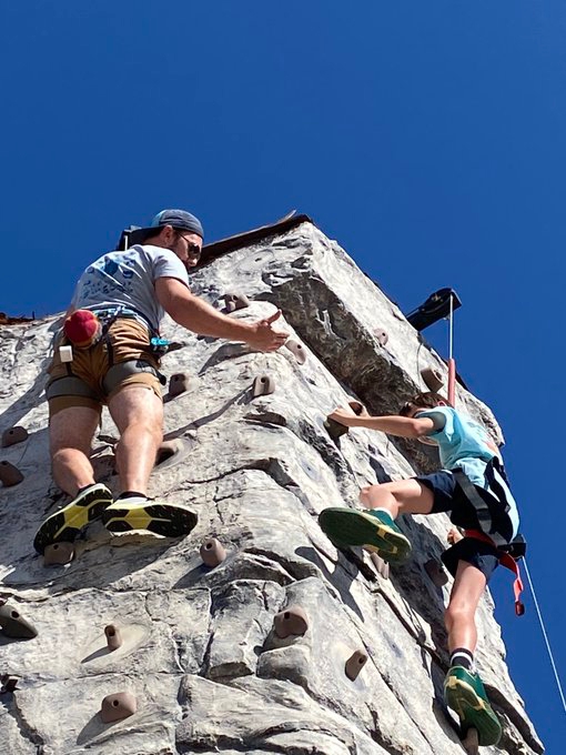 2 people climbing at the top of a rock wall