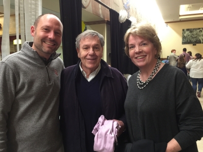 Man in gray sweater, man in middle in dark sweater, woman on the right wearing a gray sweater all smiling