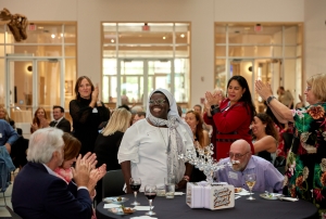 Sister Rosemary standing at table while people applaude