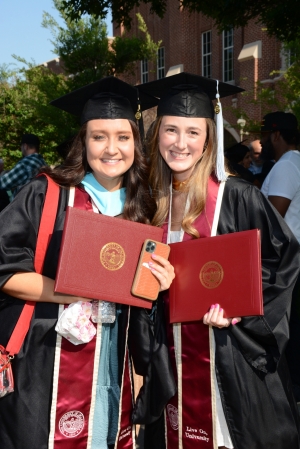 two students posing with diploma cover