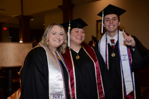 Three students standing and posing together before graduation
