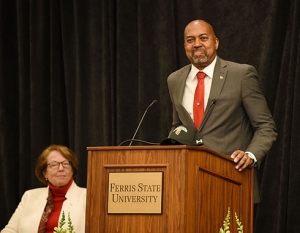 Bill Pink in grey suit standing at a podium