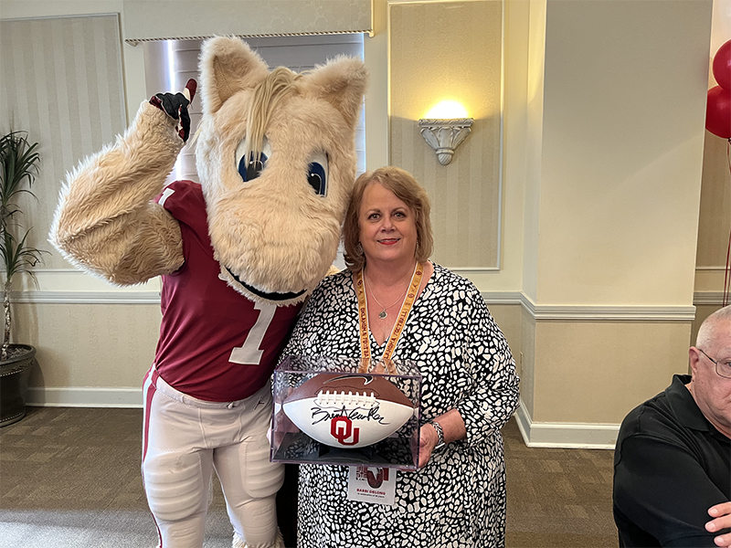 Boomer mascot standing with woman who is holding a football