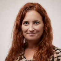 Picture of a woman with red hair in a black and tan blouse