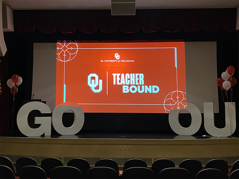 Red screen on a stage with the words OU Teacher Bound in white