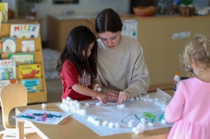 Three babies laying on a floor looking at themselves in a mirror