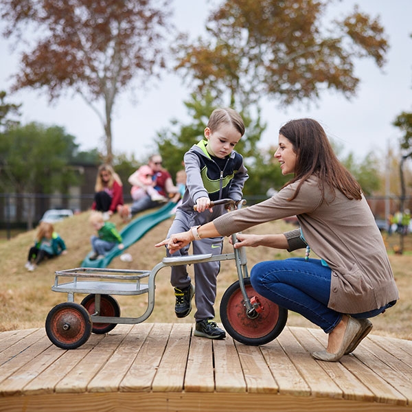 A teacher helping a student with a tricycle.