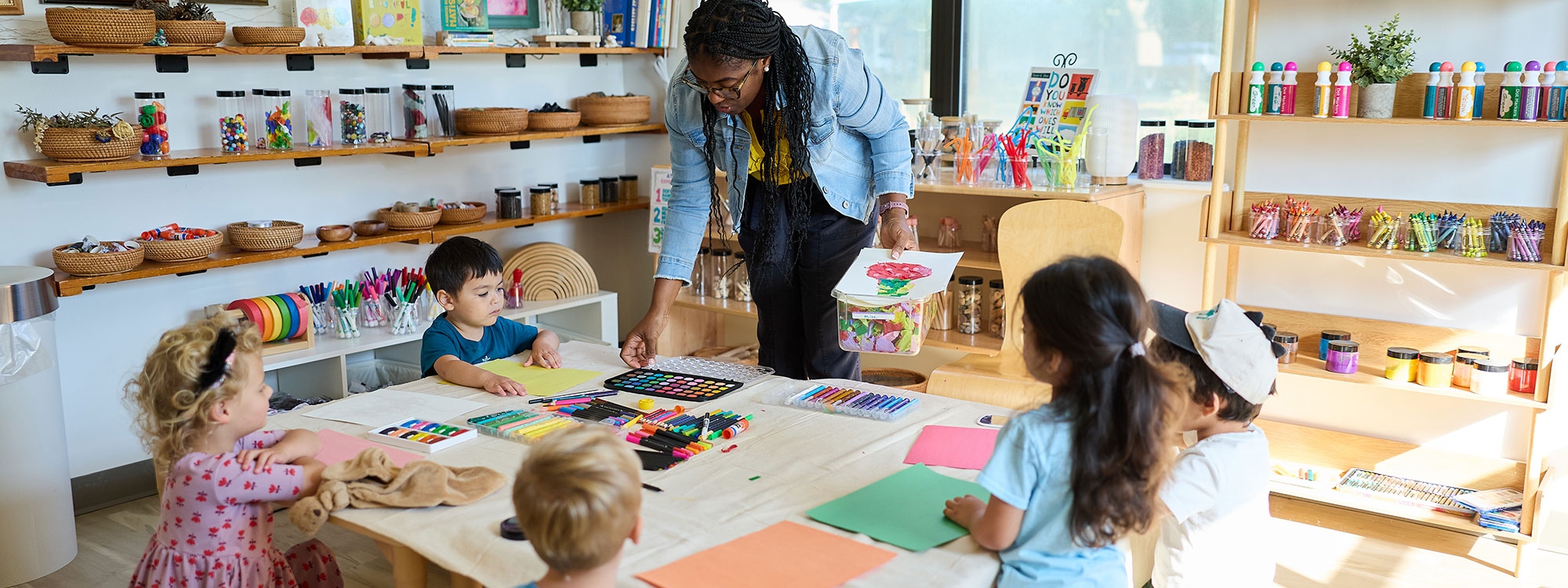 A teacher doing arts and crafts with young students.