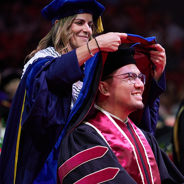 Student taking notes and listening to their lecture.
