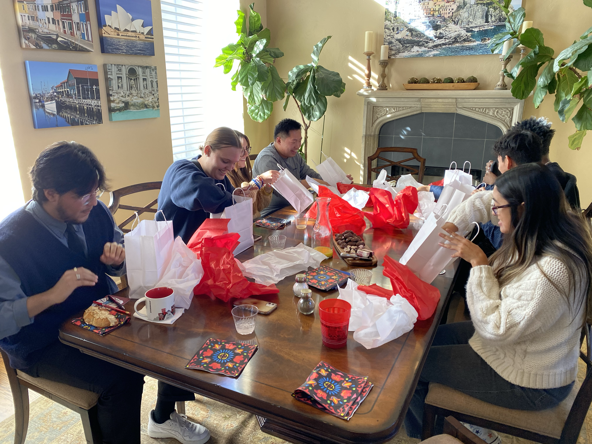 A group of students sitting at a dining room table opening gift bags