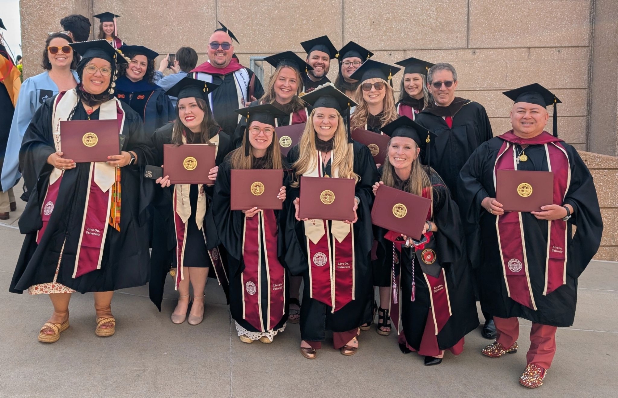 Spring 2025 Graduate Class with Faculty Members. A formal class group photo with graduating students and faculty standing together, dressed in professional graduation attire. 