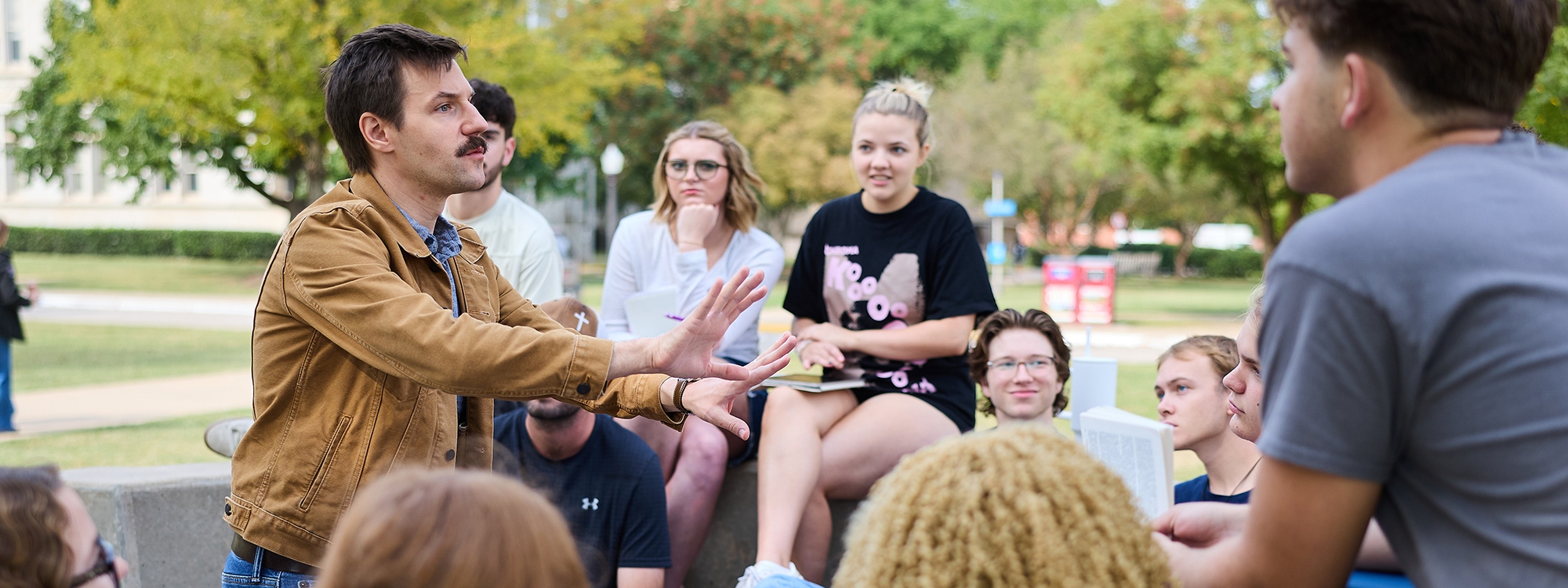 A drama professor teaching students outside.