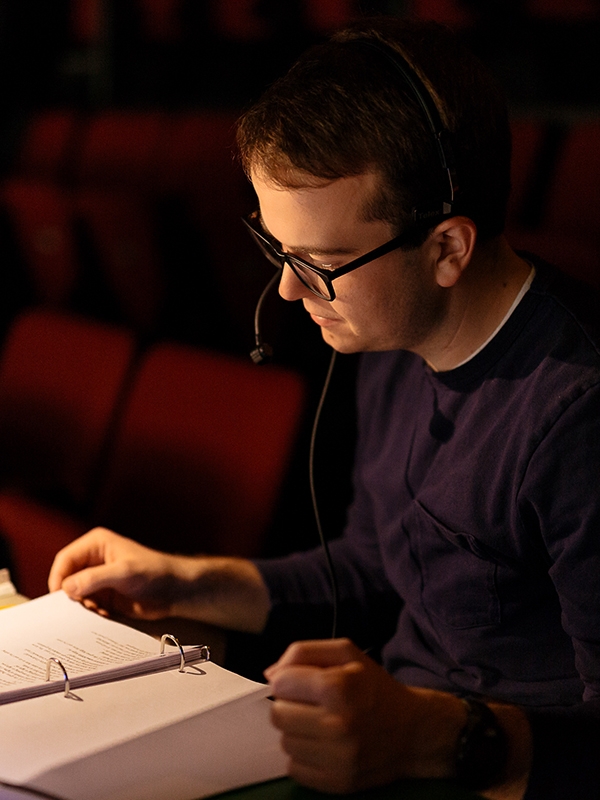 A person wearing a headset, flipping through a binder with pages.